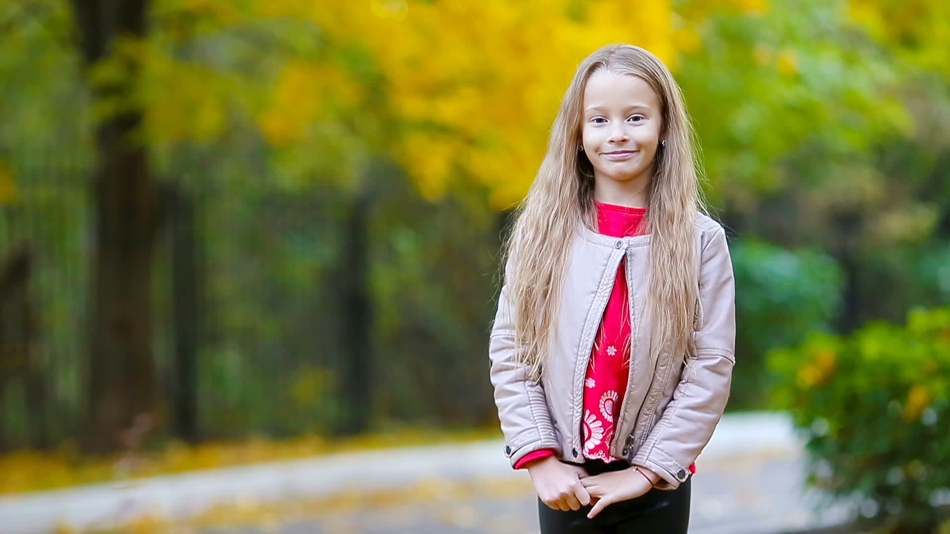 可爱的小女孩的肖像在秋天倒在地上看着镜头微笑着视频的预览图