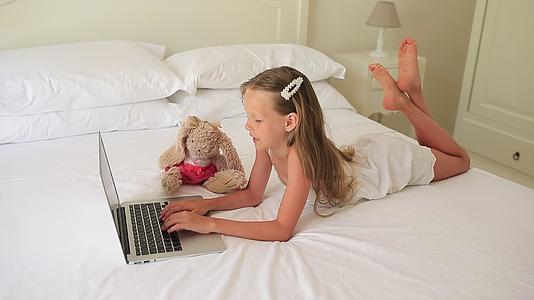 可爱的小女孩在笔记本电脑上做家庭作业视频的预览图