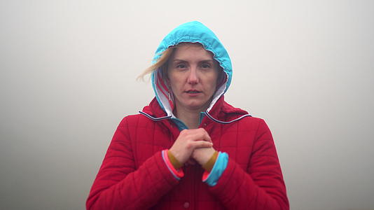 山上女孩和登山者的视频肖像戴着头罩秋天的寒冷天气充满了雾视频的预览图