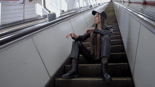 一个美丽的年轻女孩坐在地铁里的自动扶梯上视频的预览图