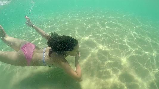 时尚模特儿女孩在水下游泳闭着鼻子慢慢地移动视频的预览图