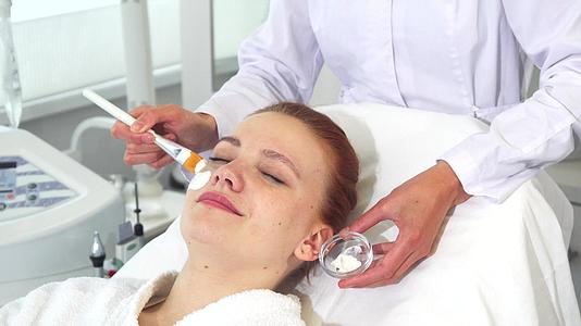 美容师在顾客脸上涂抹面霜视频的预览图