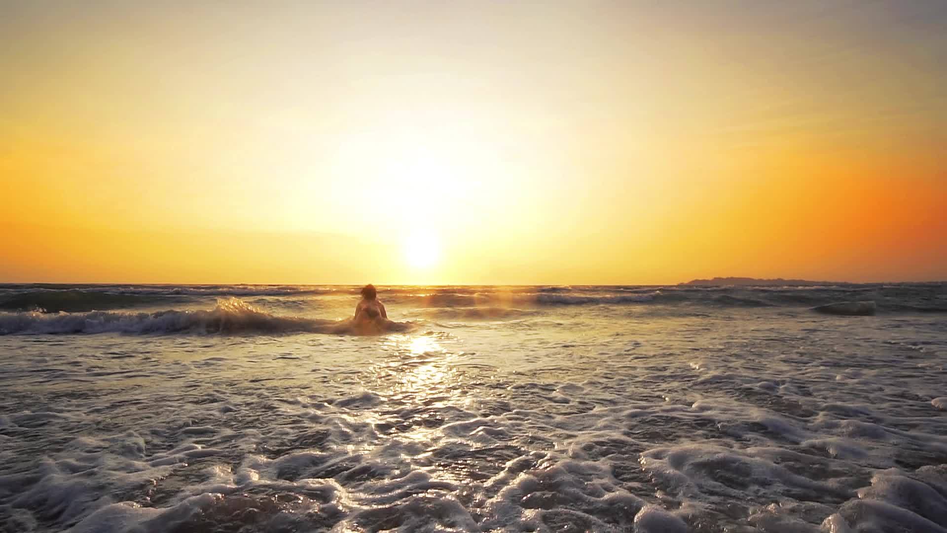 快乐的女人日落时在海滩上玩耍视频的预览图