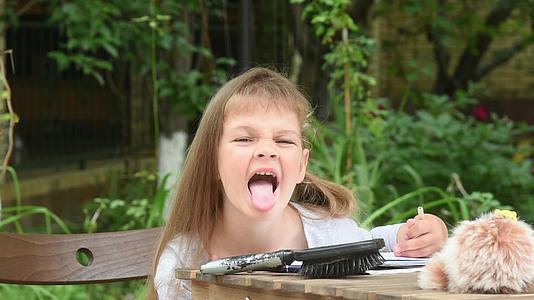 女孩坐在院子里的一张桌子上用尖利的舌头看着框架视频的预览图