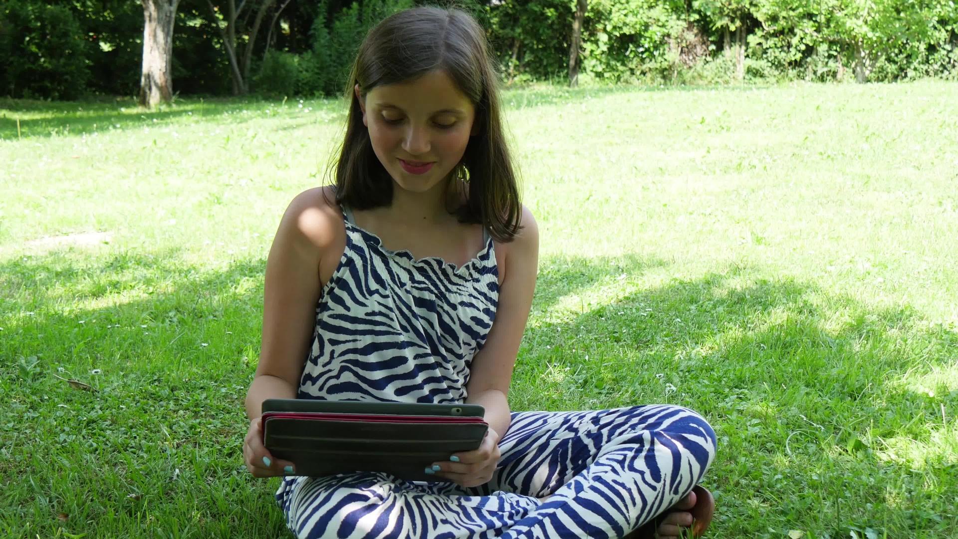 微笑的女孩在户外使用平板电脑视频的预览图
