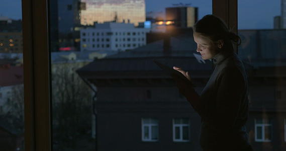 女孩晚上在窗边的墙上工作视频的预览图