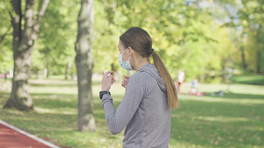 跑步女孩在公园的跑道表面戴着防护口罩视频的预览图