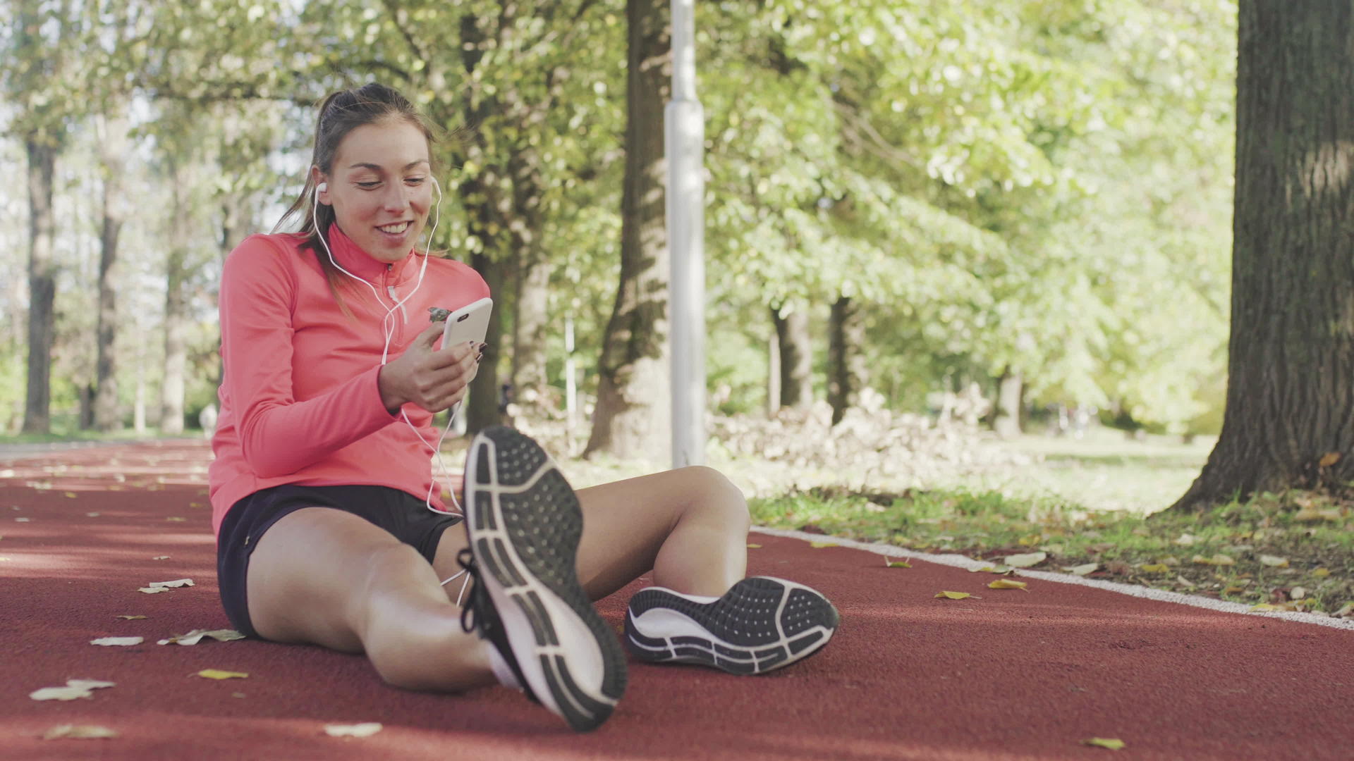 当一个健康的女孩坐在公园的天气合成轨道表面时她双腿跑步视频的预览图