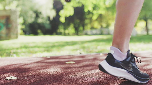 健身跑女孩在公园跑道的表面热身视频的预览图