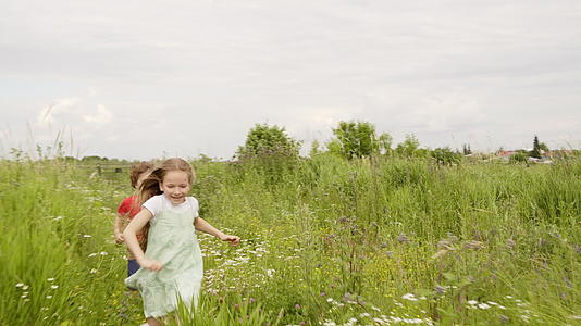 暑假期间青少年女孩和男孩在草地上玩游戏视频的预览图