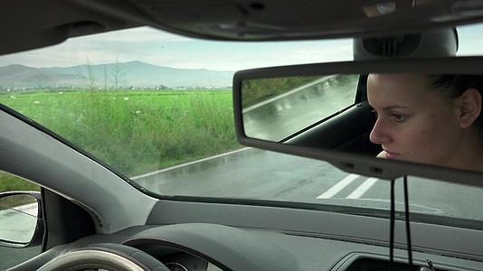 在农村道路的雨季镜像中可以看到驾驶汽车的妇女的脸视频的预览图