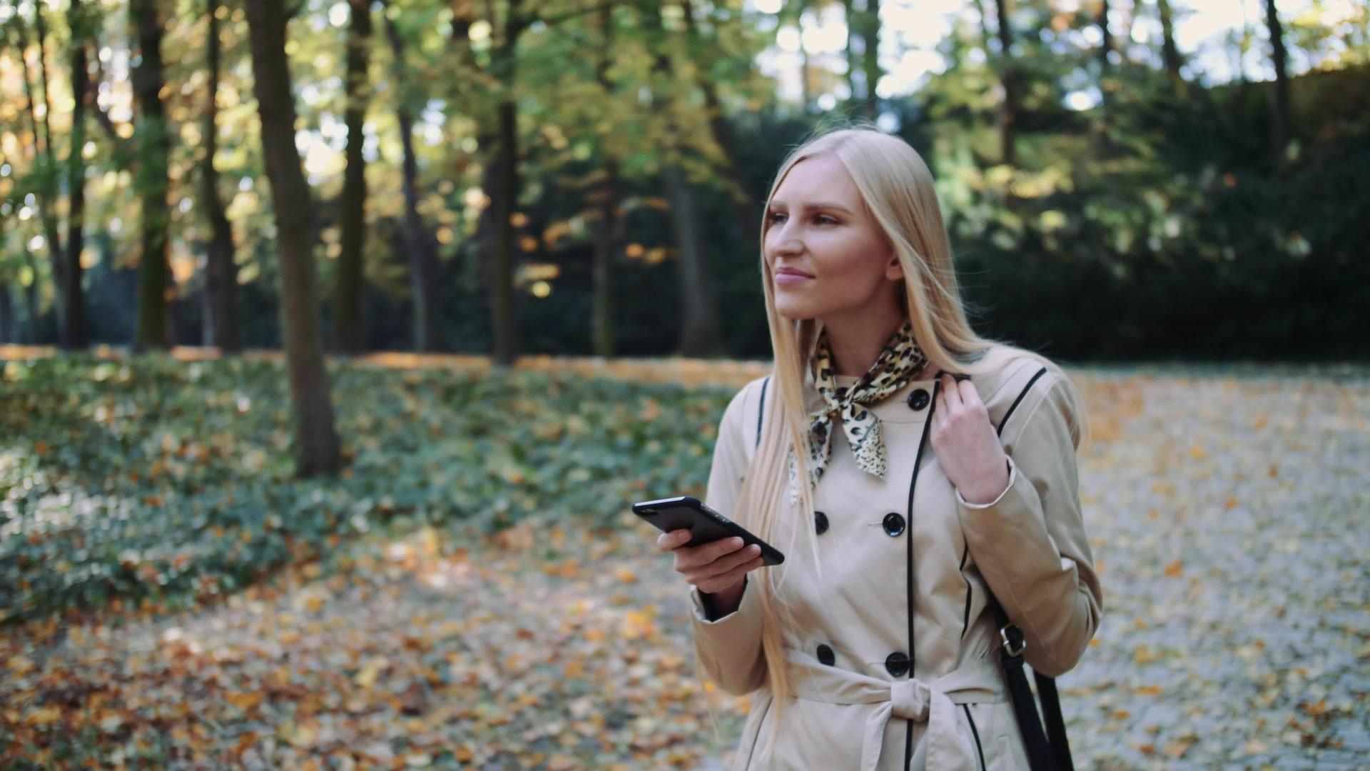 秋天女孩在公园散步在手机上发短信视频的预览图