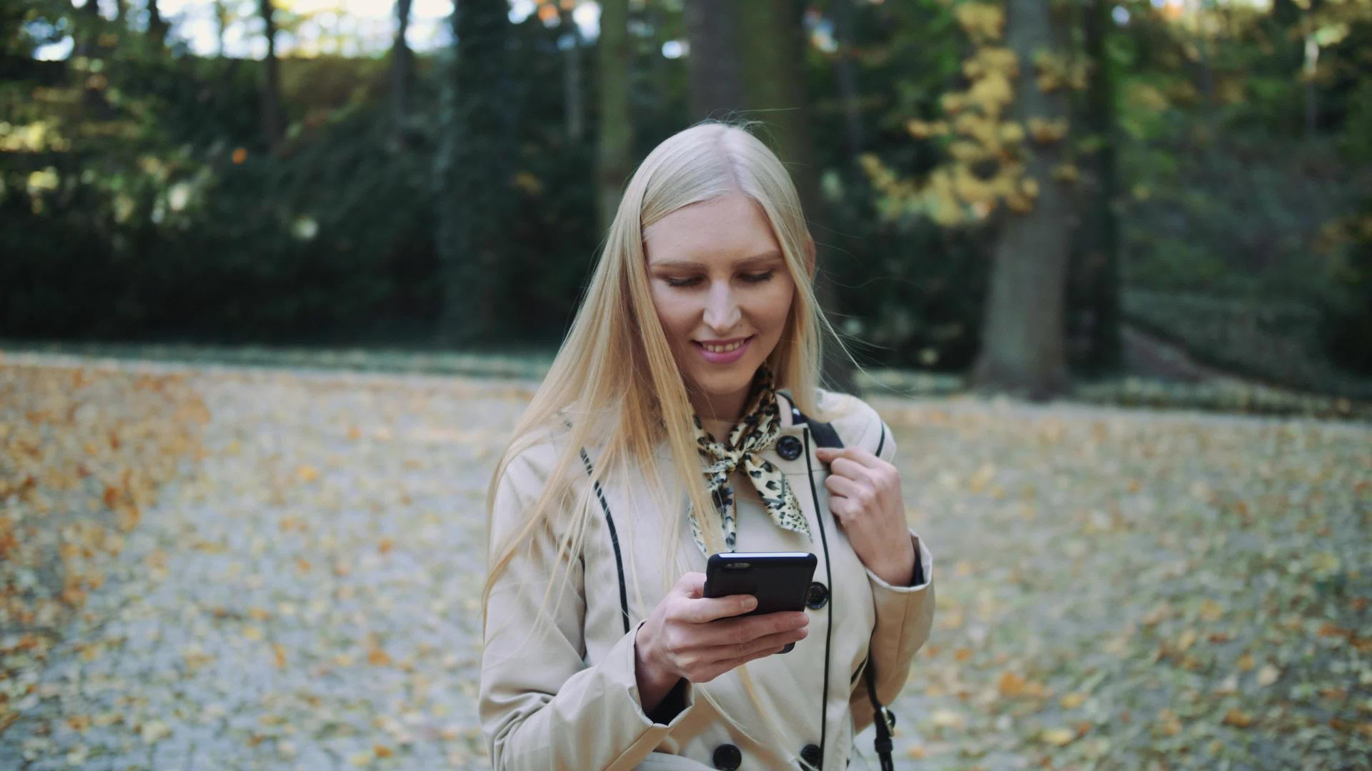 秋天金发女孩在公园里散步慢慢地把金叶扔进空中视频的预览图