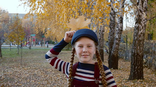 一个穿着条纹衣服和蓝色帽子的女孩头上有黄色的枫叶像乌鸦一样视频的预览图
