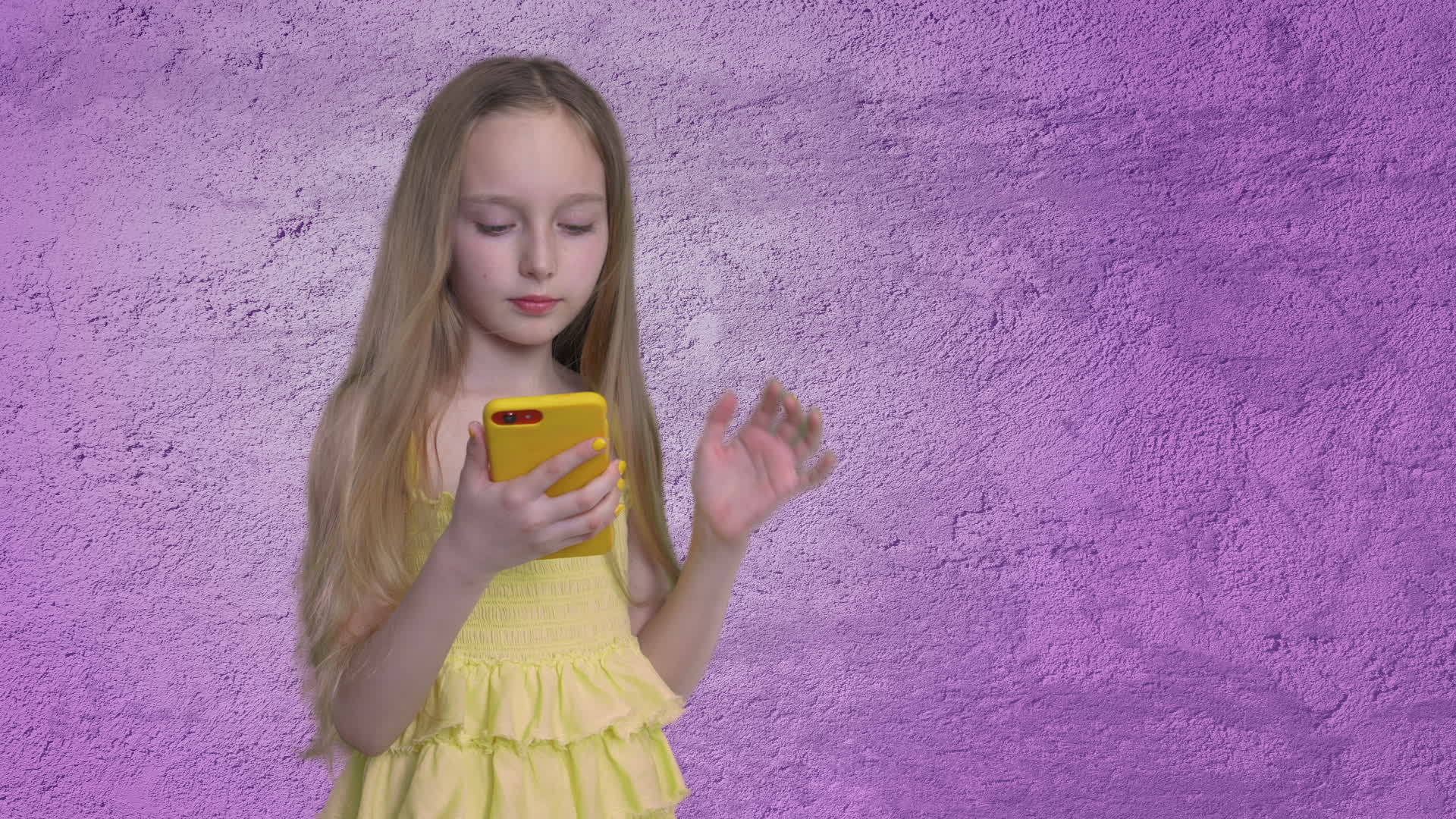 长发的金发女孩正在浏览紫色墙壁背景上的智能手机视频的预览图