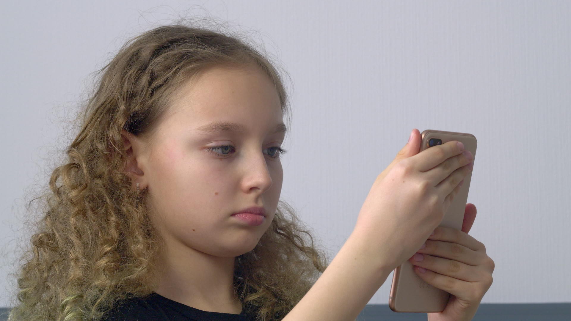 关闭了专注的女孩看着手机屏幕看着年轻的卷发女孩的手视频的预览图