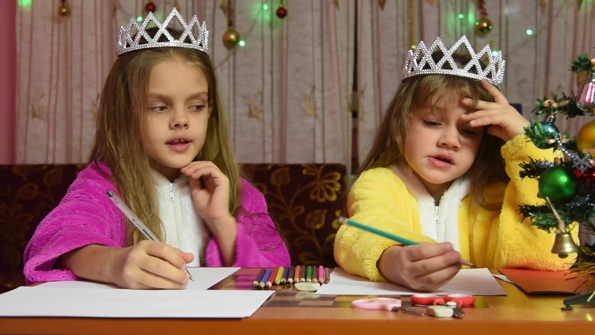 两个穿着衣服的女孩坐在桌子上写信给圣塔克劳斯的一个视频的预览图