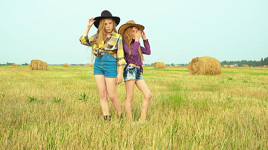 戴着牛仔帽的女孩站在农村的田地上视频的预览图
