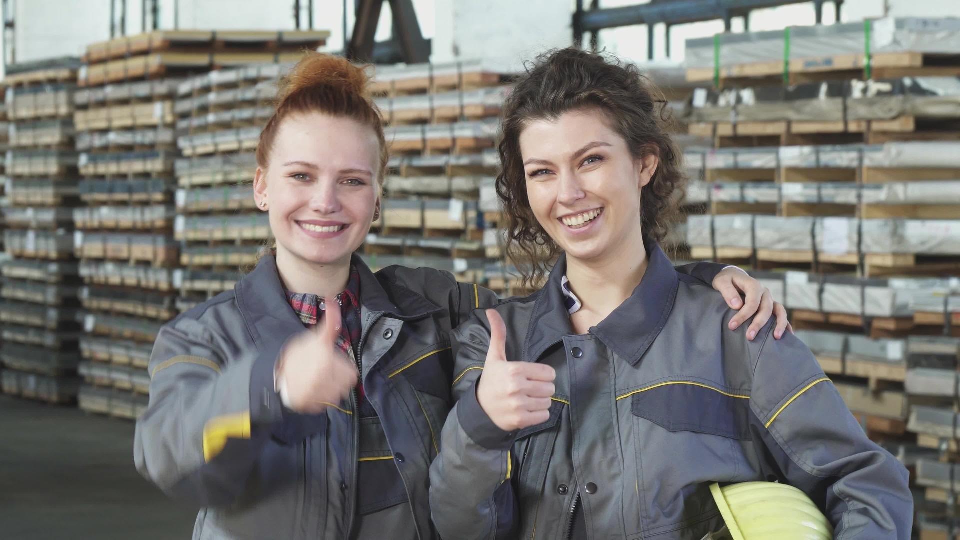 两个快乐的女工厂工人喜欢在仓库里露出拇指...视频的预览图