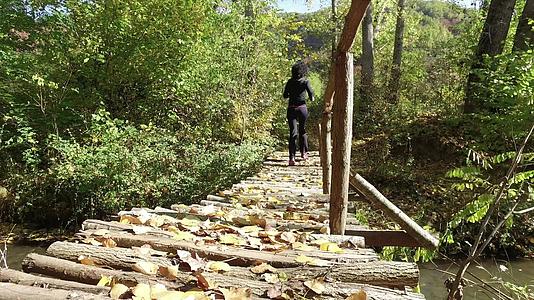 美丽的年轻女子在木桥上的森林公园里跑来跑去视频的预览图