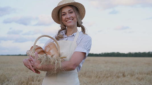 女农站在小麦农田女面包师拿着柳条面包烘焙生态产品视频的预览图