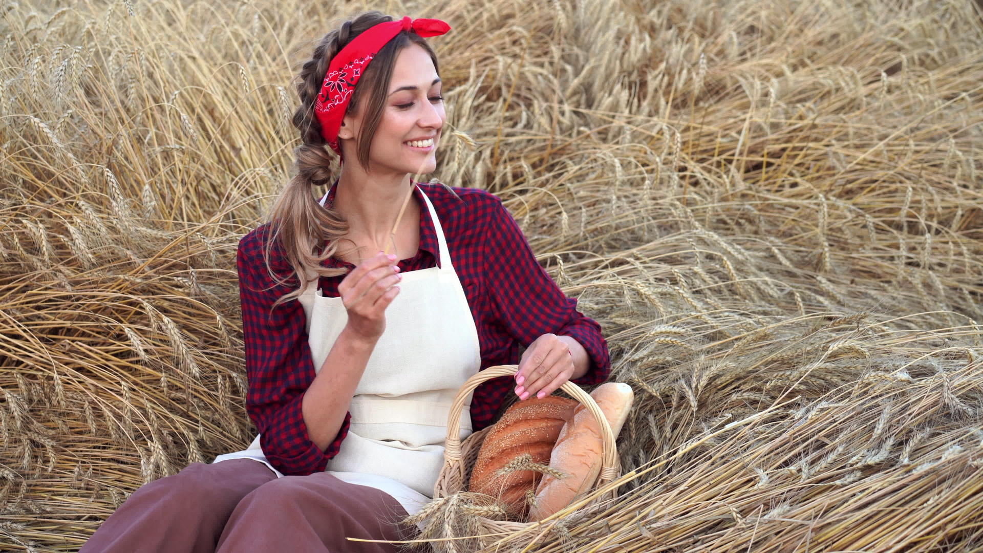 女农坐在小麦农场女面包师拿着柳条面包烘焙生态产品视频的预览图