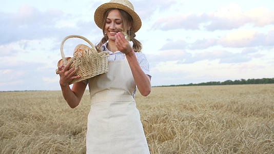 女农站在小麦农田女面包师拿着柳条面包烘焙生态产品视频的预览图
