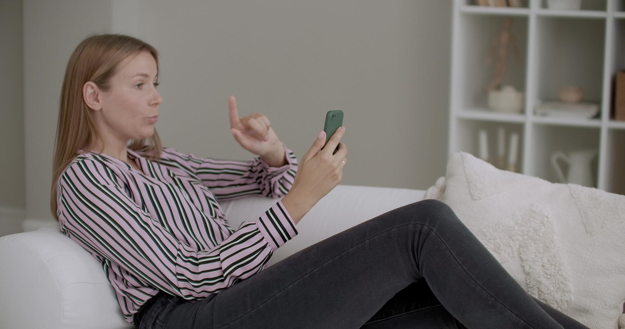 女性博客与在家使用智能手机的追随者聊天并与电视聊天视频的预览图