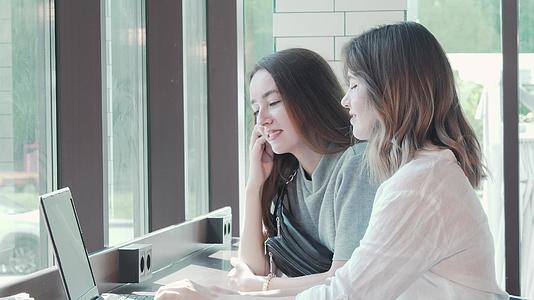 两名年轻女性在校园咖啡馆用笔记本电脑学习视频的预览图
