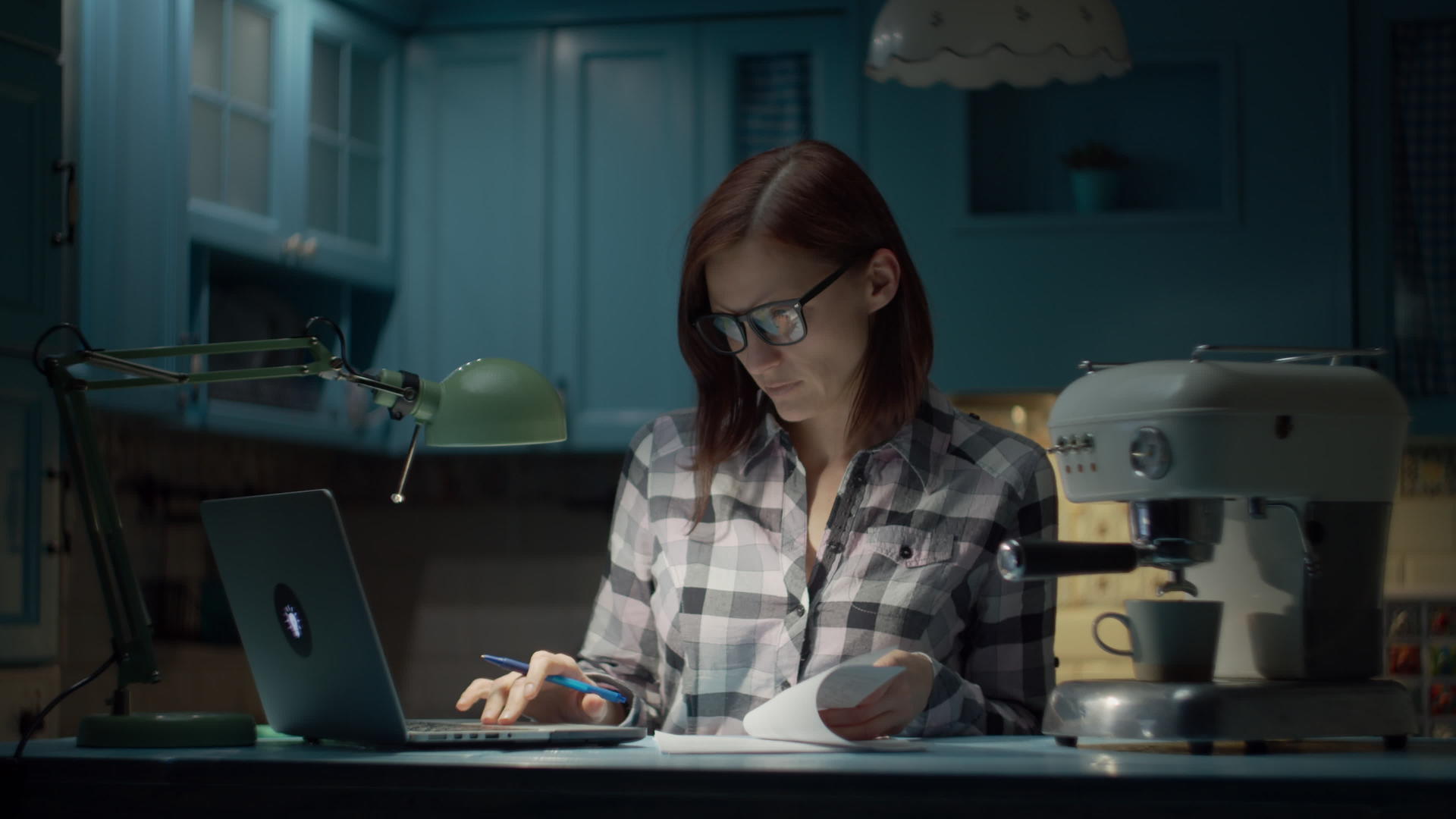 这位年轻女子戴着眼镜晚上在蓝色厨房的家里用笔记本电脑视频的预览图