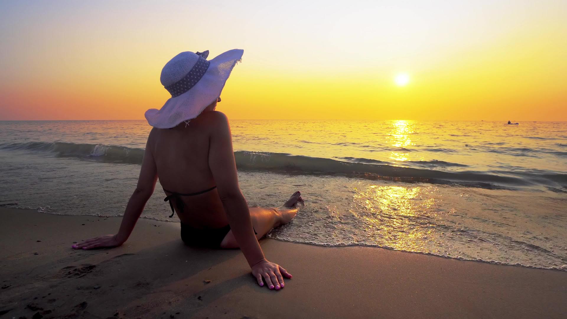 日落时坐在海滩上的西班牙女人视频的预览图