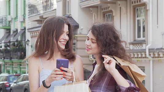 两位快乐的年轻女性在户外智能手机上浏览网络视频的预览图