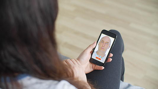 在家在线医疗咨询期间女性手持手机医生在远程治疗期间视频的预览图