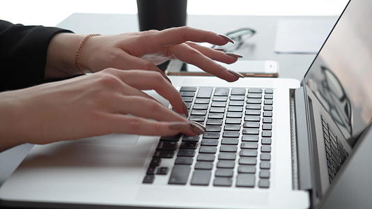 女性用手在桌子上的笔记本电脑键盘上打字视频的预览图