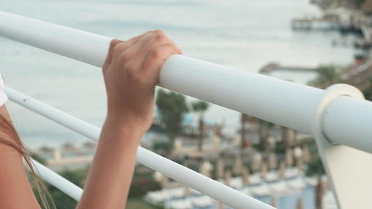 女人的手在白色栏杆阳台上上面有海景视频的预览图