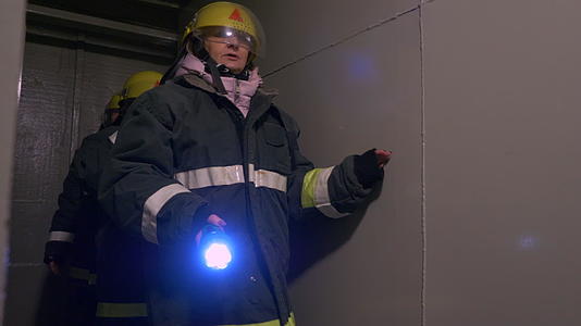 女救援人员穿着防护服和头盔手持手电筒进入隧道视频的预览图