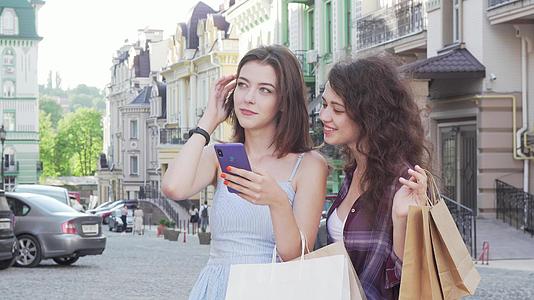 两位年轻女性朋友使用网上地图在城市街道智能手机上使用视频的预览图