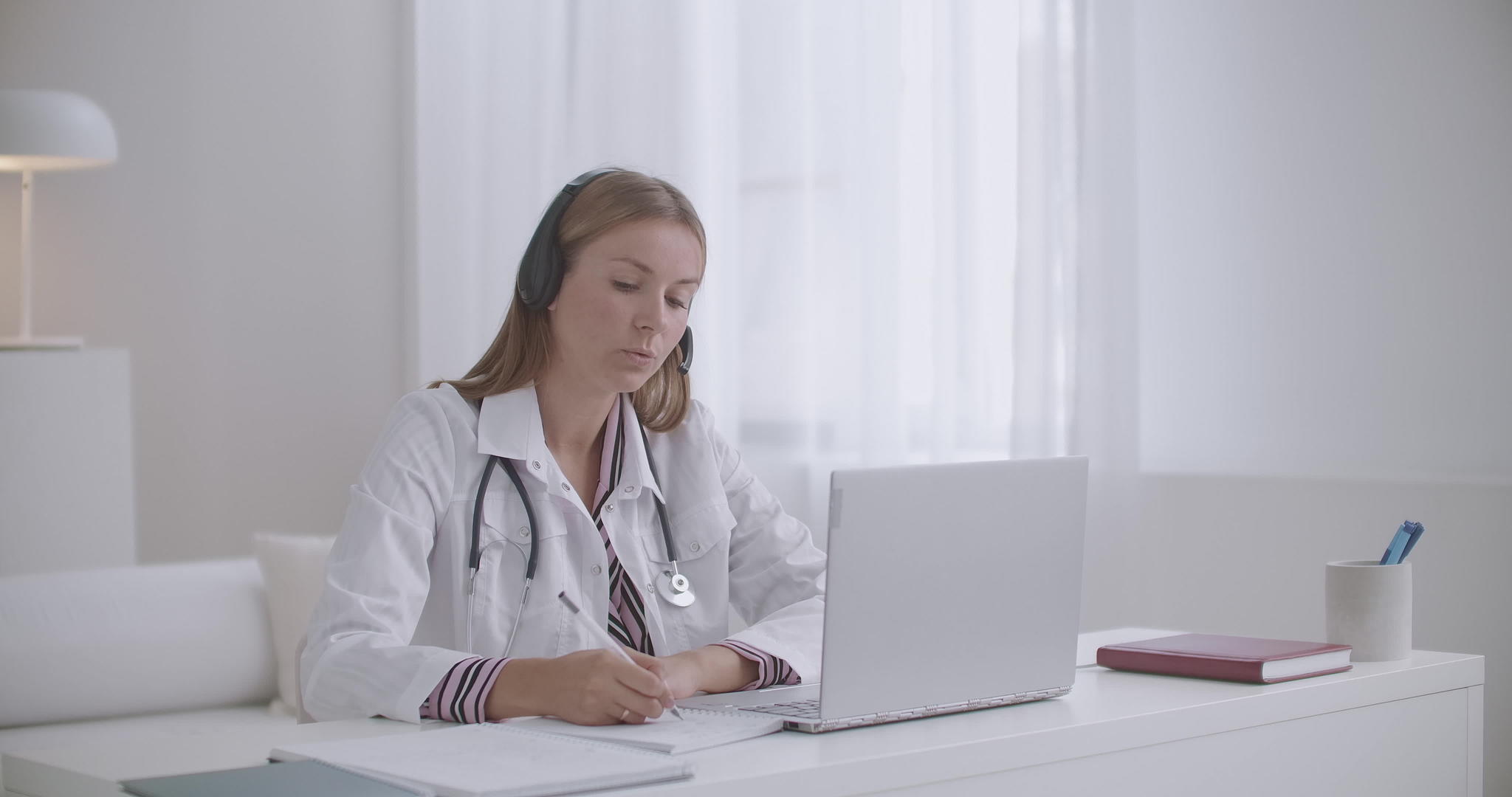 年轻女性治疗师正在网上咨询患者并在复印本上做笔记视频的预览图