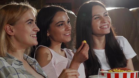 三个美丽的年轻女子在电影院的相机上微笑着视频的预览图