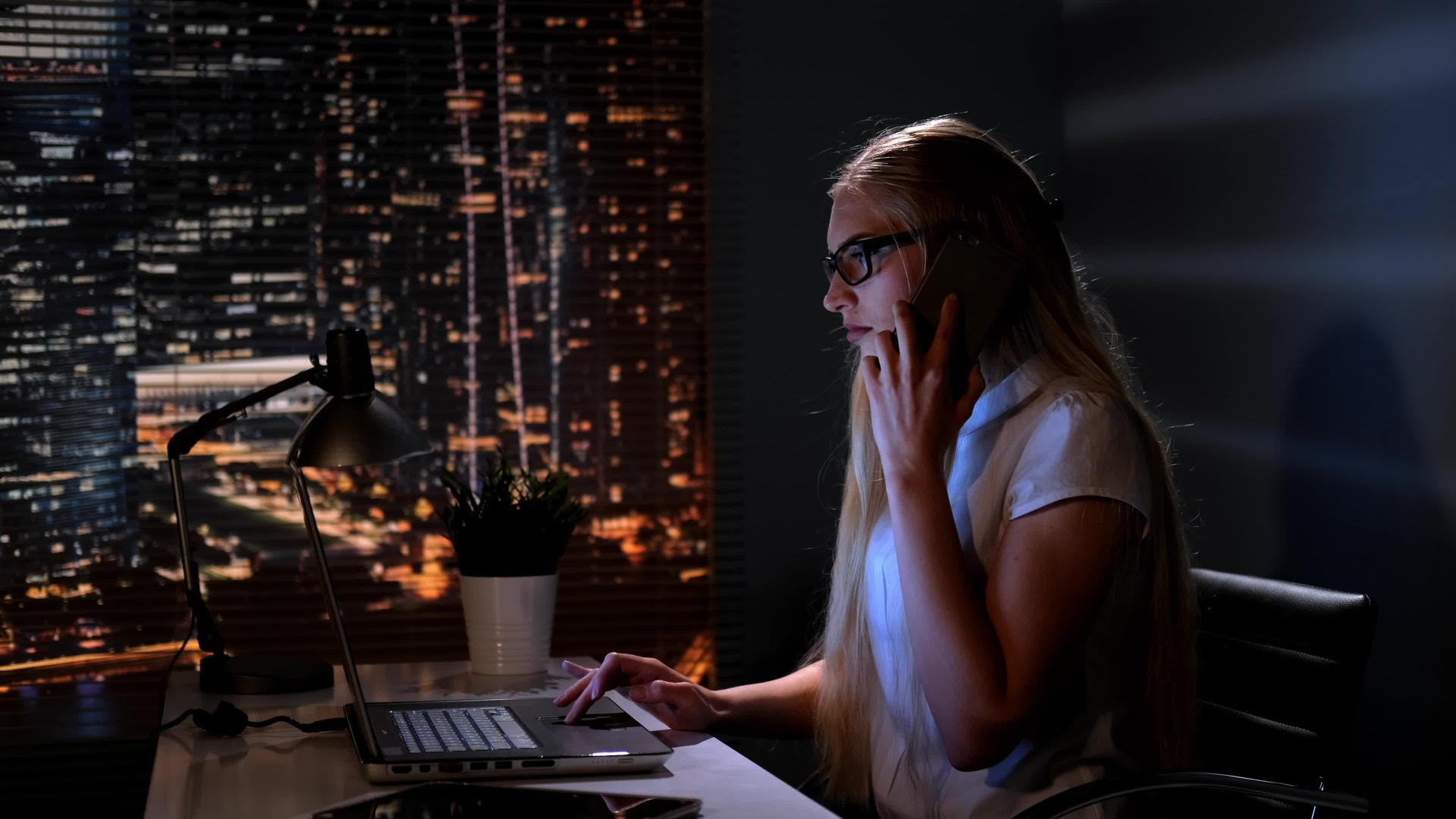 年轻的女经理在电脑上工作用智能手机和某人交谈使用B使用视频的预览图