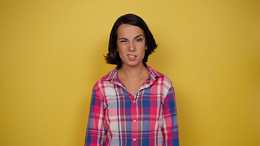 穿着黄色背景格子衬衫的女性有利于人类的面部表情视频的预览图