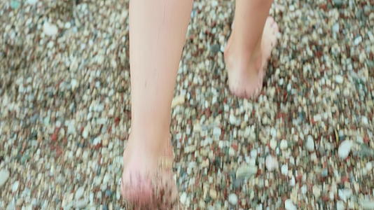 暑假期间在鹅卵石海滩散步的女性腿关闭了赤脚女孩的脚在夏天踩了她们的脚视频的预览图