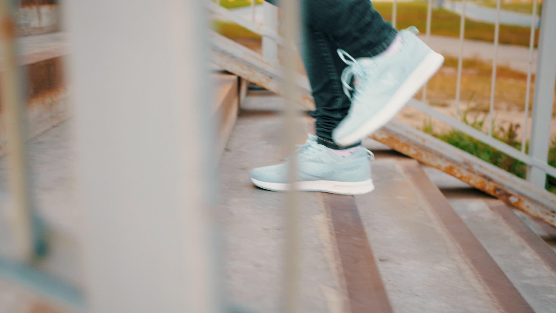穿着运动鞋和蓝色牛仔裤的女人穿着运动鞋在户外楼上行走视频的预览图