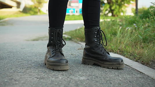 夏天站在柏油路上穿着黑色皮靴的女孩的腿穿着皮鞋视频的预览图