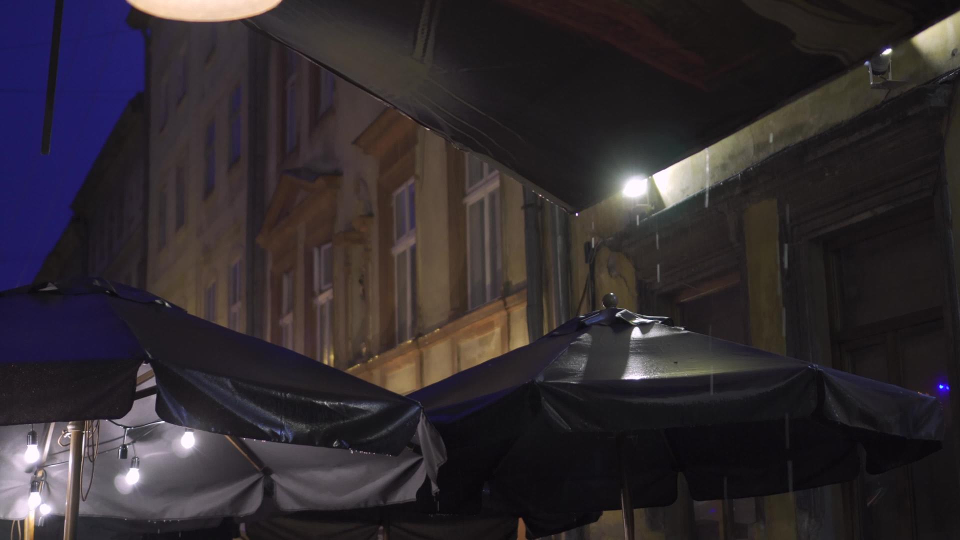 欧洲老城街露天咖啡馆的树冠上下倾盆大雨晚上在暴雨中视频的预览图