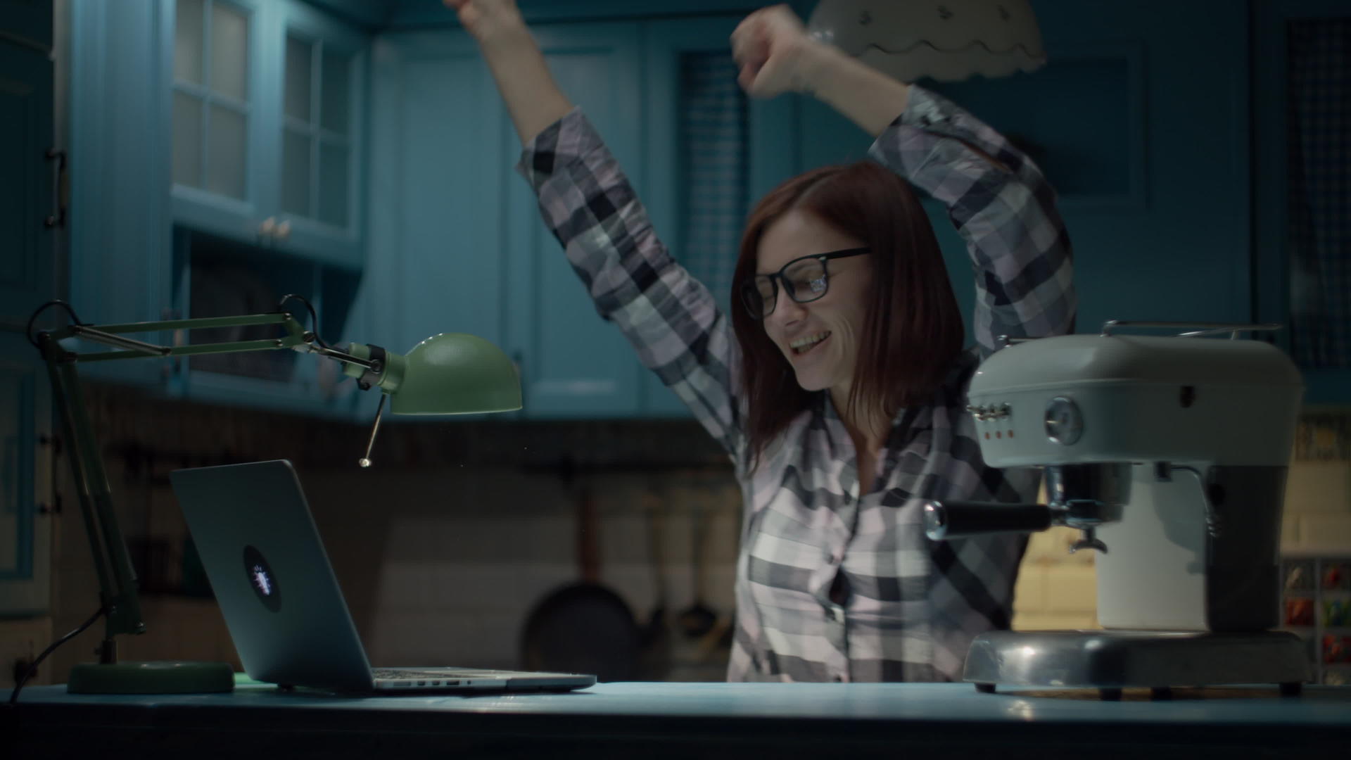 30多岁的年轻女性戴着眼镜深夜在蓝色厨房里跳舞视频的预览图