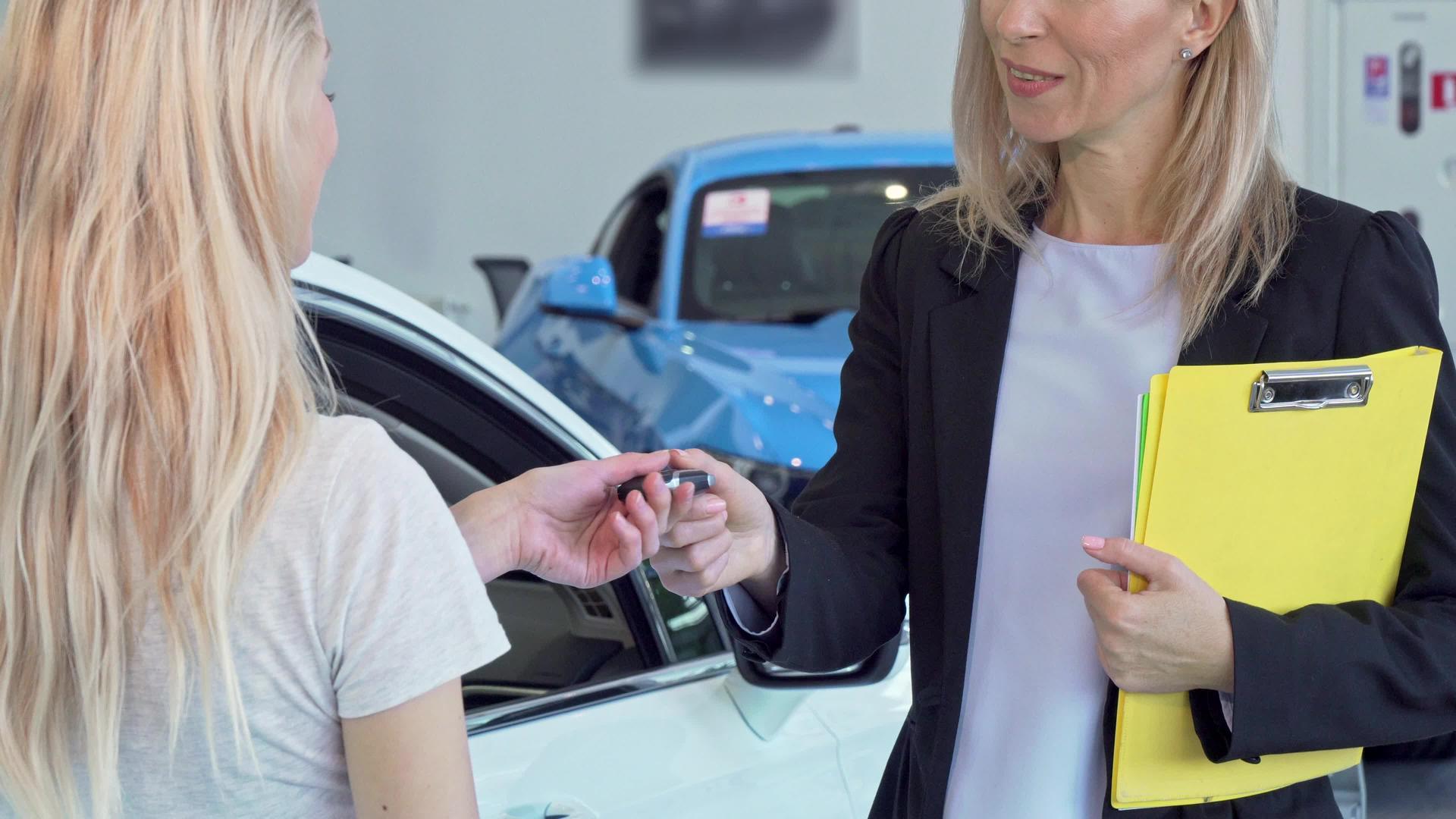 女性顾客接受汽车钥匙并与销售女性握手视频的预览图