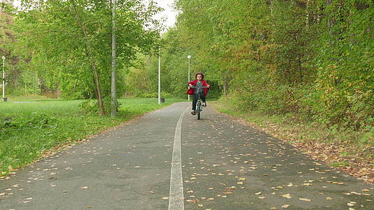 小男孩骑自行车的人在绿色夏日公园的小路上骑自行车视频的预览图
