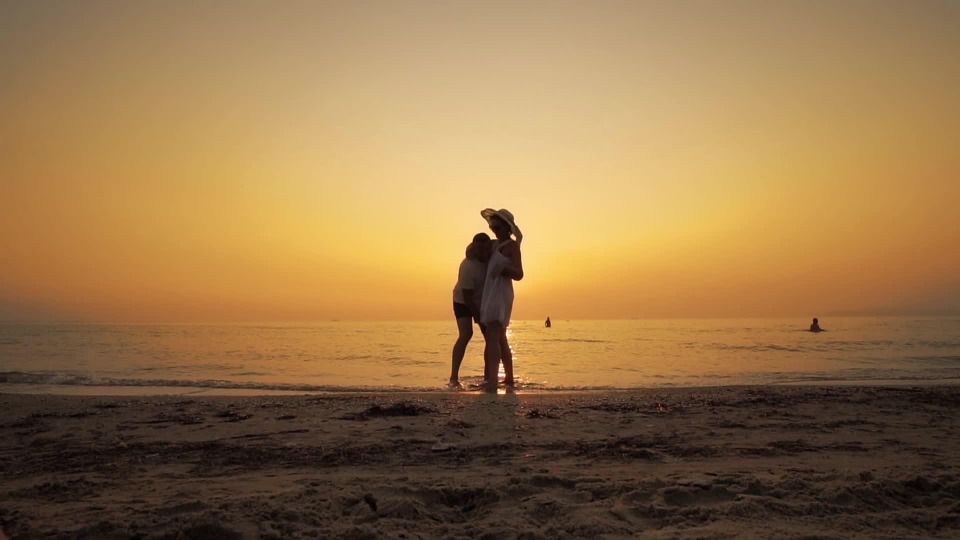 幸福的夫妇在日落时分在海滩上玩耍男人抱着一个穿着白色衣服的男人视频的预览图