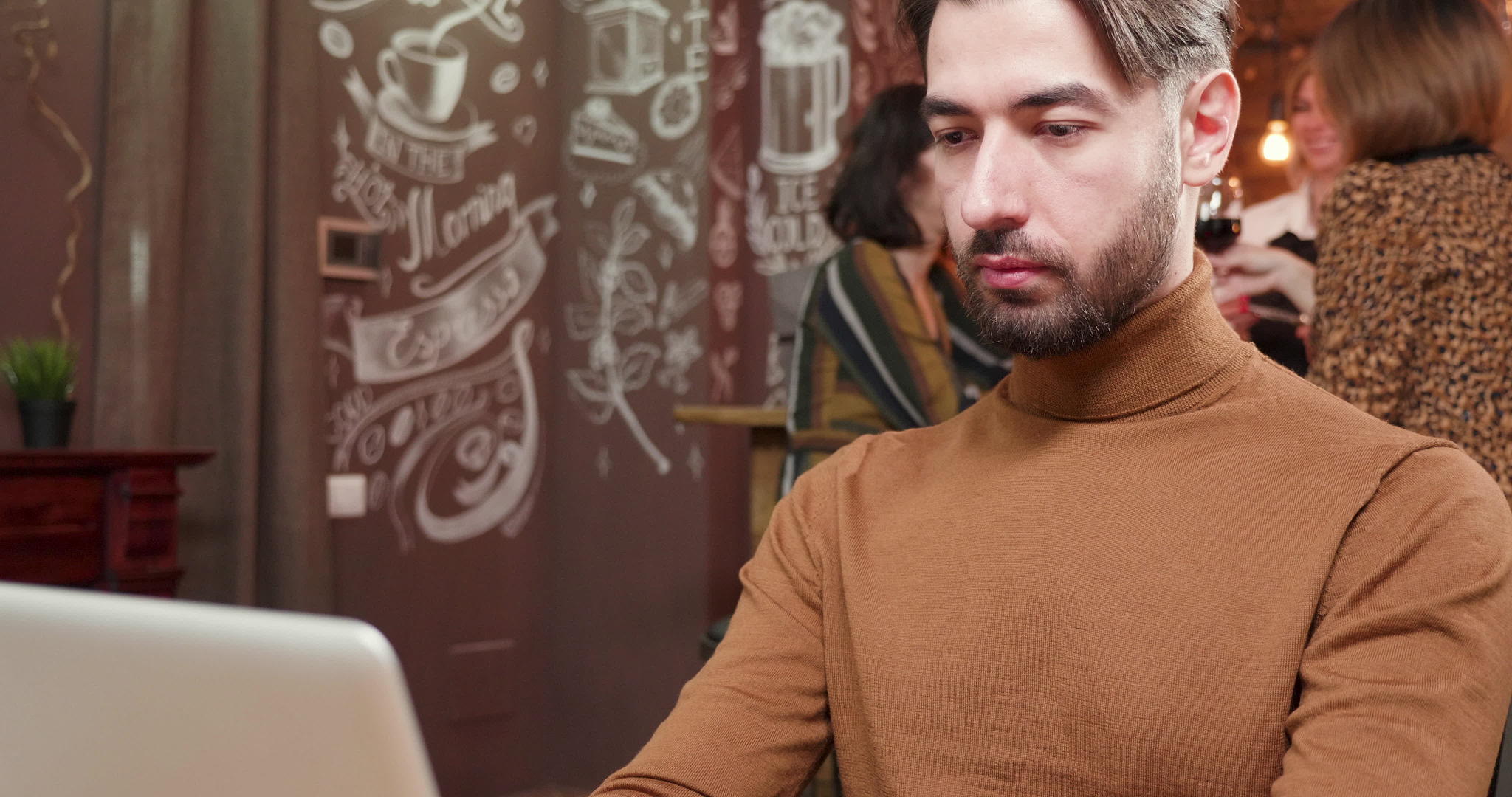 英俊的年轻人一边喝咖啡一边在电脑上工作视频的预览图